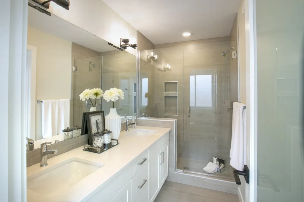 Bathroom in a custom built home with a glass walk-in shower, white vanity, and large mirror in Edmonton