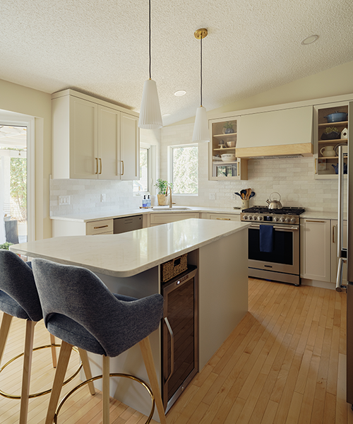 Custom kitchen island with quartz countertop and bar stools, pendant lights overhead — kitchen renovation in Spruce Grove, AB