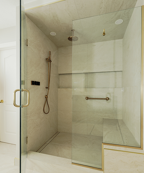 Interior of a renovated walk-in shower with marble tile walls, brass slide bar, hand shower, grab bar, and linear drain.