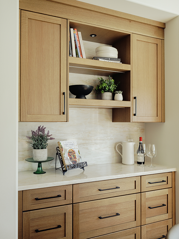 White oak shaker cabinets with open shelving, matte black hardware, and a light stone backsplash above a quartz counter.