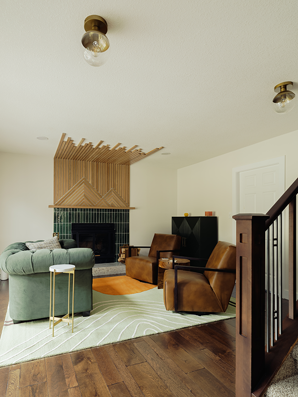 Living room renovation showing a wood slat fireplace feature wall, dark hardwood floors, staircase railing, and brass globe ceiling fixtures.