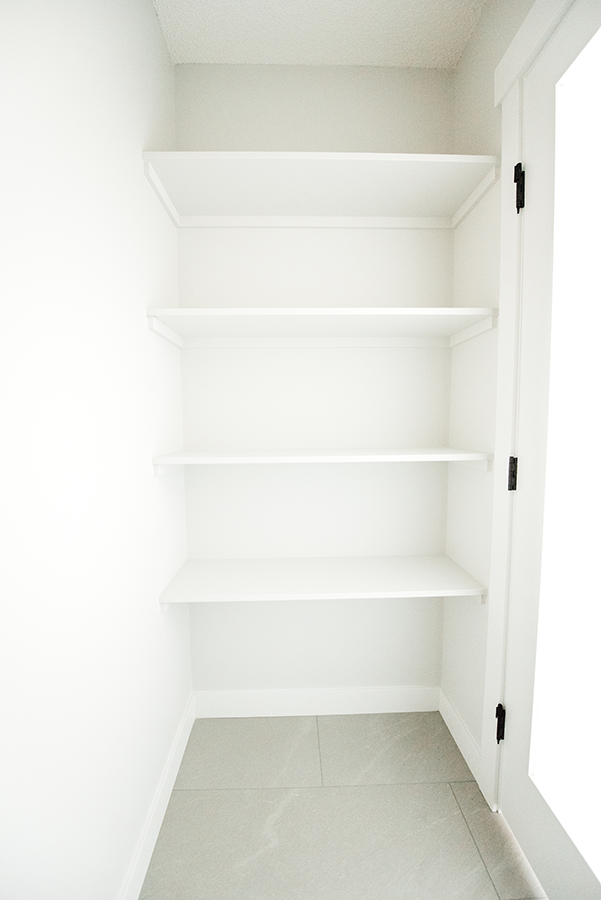 Built-in shelving inside the separate water closet of the primary ensuite — practical storage in Edmonton second-story home addition