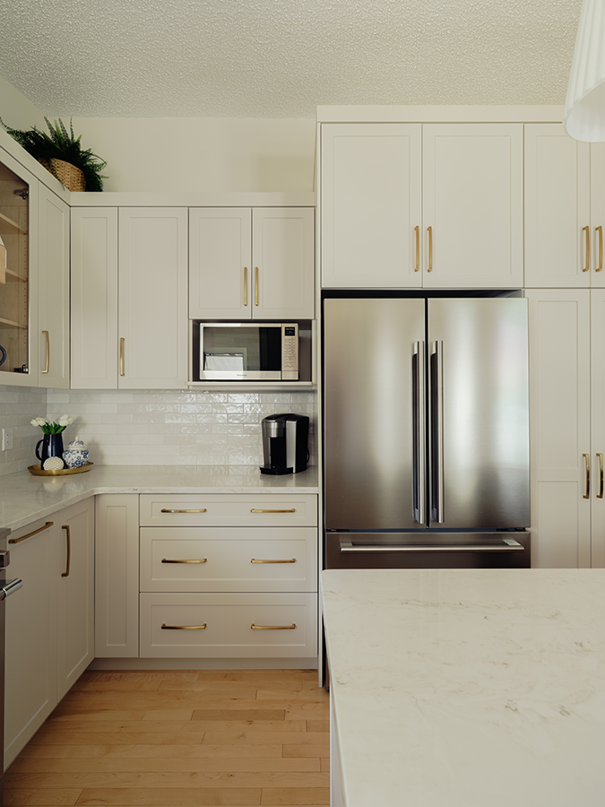 Stainless French door fridge flanked by floor-to-ceiling white cabinetry and pantry tower — kitchen renovation in Spruce Grove, AB