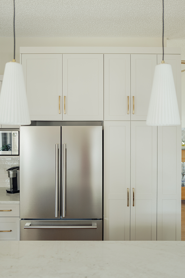 Stainless French door fridge with floor-to-ceiling cabinetry framed by white pendant lights — kitchen renovation in Spruce Grove, AB