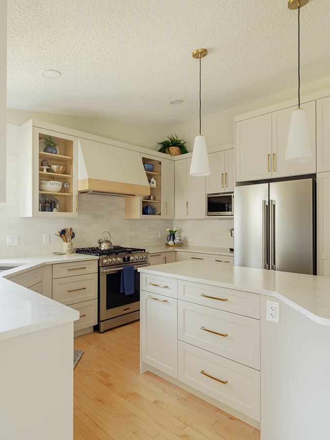 Kitchen island with quartz top, built-in fridge wall, and upper cabinetry with gold hardware — kitchen renovation in Spruce Grove, AB