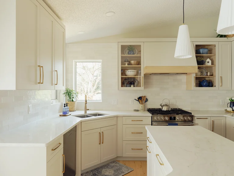 Wide view of renovated kitchen showing sink, gas range, hood valance, and glass-front upper cabinets — kitchen renovation in Spruce Grove, AB